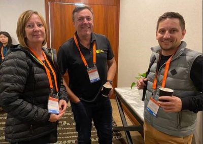 Three people standing next to each other in a conference room discussing construction management software.