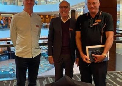 Three men in Australia standing in front of a table with a bag.