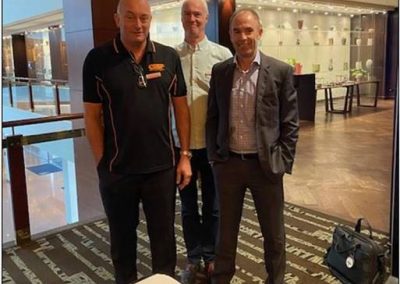 Three men, possibly construction managers or individuals from the construction industry, standing next to each other in a lobby.