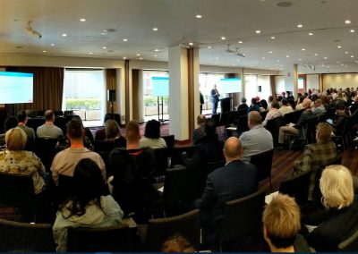 A room full of people watching a construction management presentation.