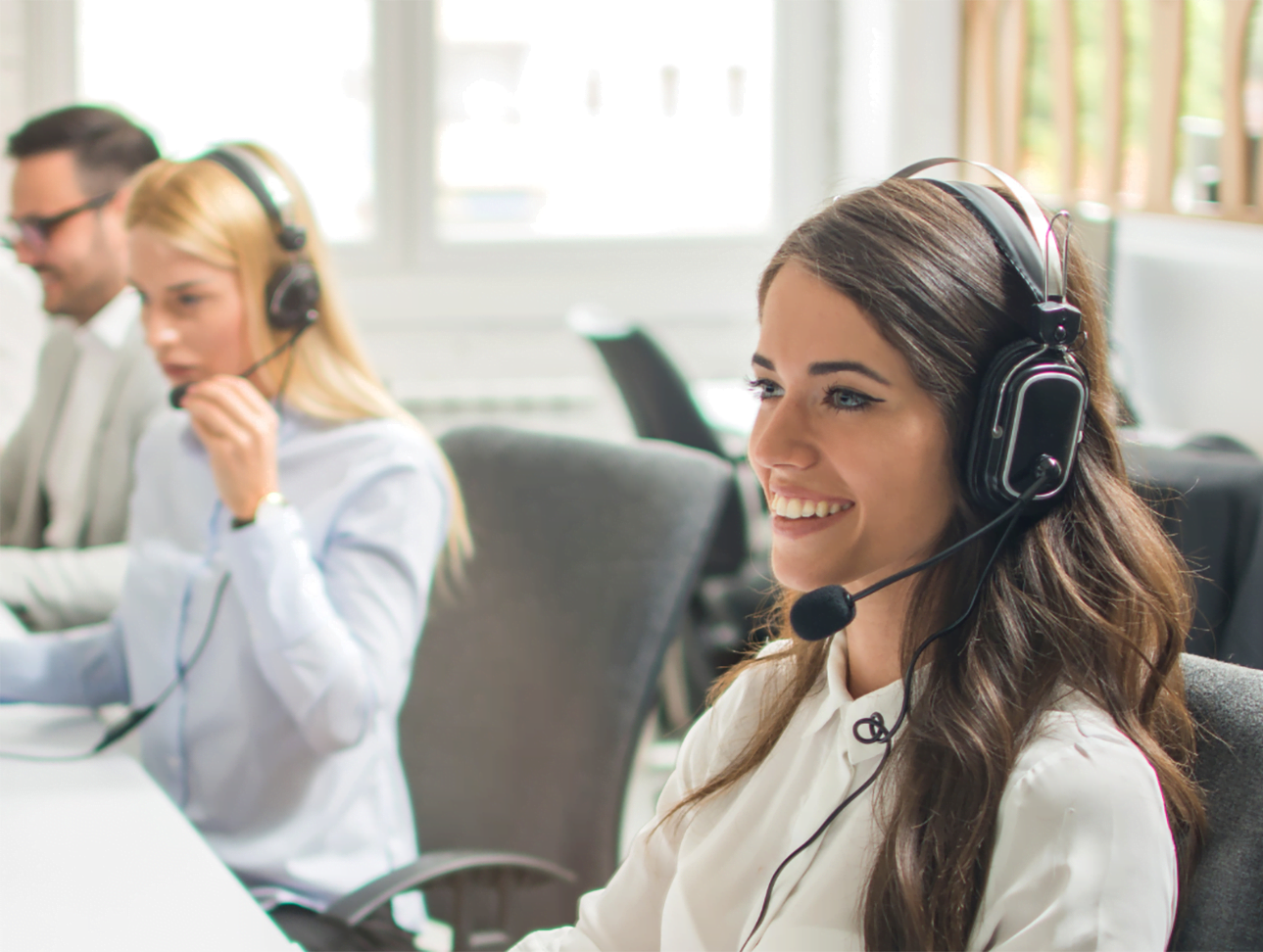 A group of people wearing headsets in a call center. A group of people wearing headsets in a call center.